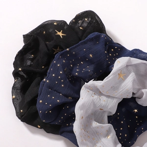 Gros plan sur des chouchous en mousseline à motif d'étoiles avec imprimé doré brillant