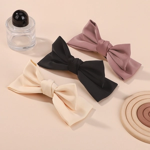 Three-piece set of elegant matte satin bow hair clips in pink, black, and creamy white