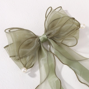 Détail d'un nœud papillon vert clair en mousseline avec perles blanches élégantes