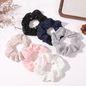 Détail de cinq chouchous colorés avec motifs étoiles dorées sur un fond blanc pur
