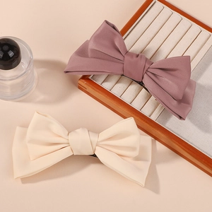 Detail of rose and cream fabric bow hair clips with spring metal clasp on a soft background