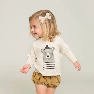Detail of cream lace bow hair clip on model with rustic bear print autumn outfit