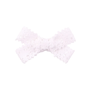 Close-up detail of white floral lace bow hairclip with intricate hollow patterns