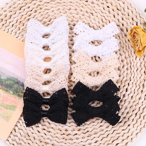 Three-piece set of lace bow hair clips in white beige and black on a woven mat