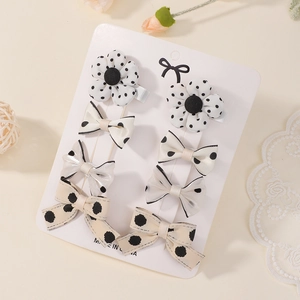 Détail du lot de huit barrettes pour enfants avec fleurs et nœuds à pois blancs et beige