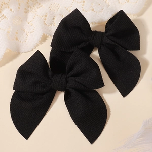 Close-up of black textured bow hair clips with ribbed fabric details for girls