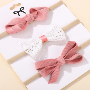 Detailed texture of pink corduroy and white lace bow headbands for baby girls