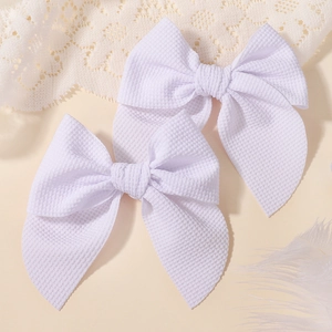 Detailed macro view of white waffle textured fabric hair bows for girls hair clip set