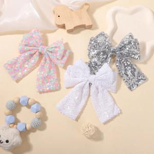 Sparkly sequin bow hair clips for girls in pink, silver and white on a warm tray