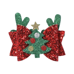 Close-up of Christmas hair clip with red sequin bow, green glitter antlers and tree