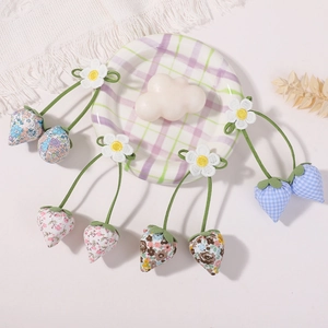 Detailed view of handmade floral strawberry hair ties with embroidered daisy accents