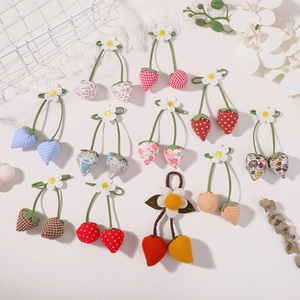 Flat lay of diverse handmade floral strawberry pendants with daisy charms and green cords
