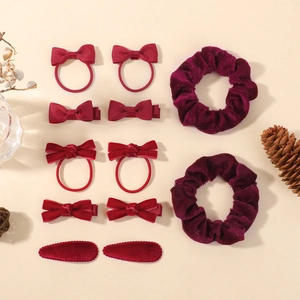 Détail de pinces à cheveux à nœuds rouges et violets et chouchous en velours sur fond doux