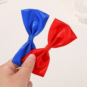 Gros plan de barrettes à nœud en satin bleu et rouge montrant la texture soyeuse