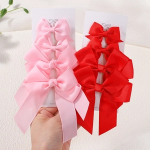 Detail of pink and red grosgrain ribbon hair bow clips with long double streamers