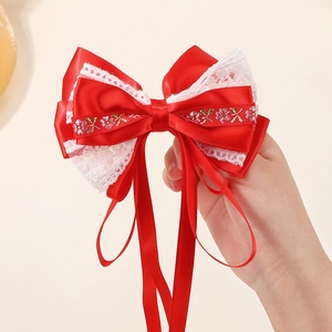 Détail du nœud rouge avec dentelle blanche, broderie florale et longs rubans en satin