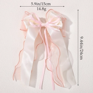 Pink and beige chiffon bow hair clip with long ribbons on white textured background