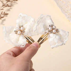 Detail van witte kanten haarspelden met parels en strass op een goudkleurige metalen klem