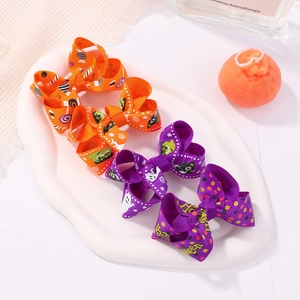 Three Halloween bow hair clips with cat and ghost prints on a white decorative tray