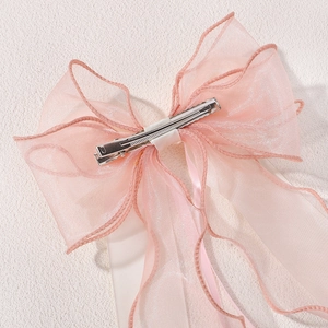 Close-up of pink layered chiffon ribbon hair clip with wavy edges and metal duckbill grip