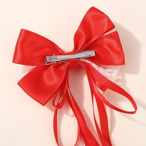 Détail d'un nœud papillon en satin rouge avec dentelle blanche et pince crocodile en métal