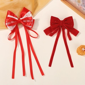 Détail de pinces à cheveux nśuds rouges avec broderie élégante et longs rubans en velours