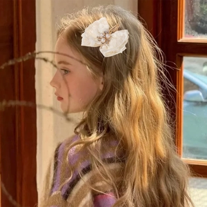 Detail van witte kanten haarspeld met parels en strass op het haar