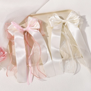 Detail of large chiffon bow hair clip with long ribbons in pink and white satin