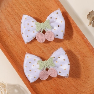Détail de pinces à cheveux en tulle blanc avec broderie cerise et paillettes