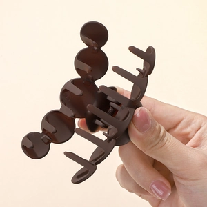 Gros plan sur la pince à cheveux marron mat avec design de silhouette Mickey à trois cercles