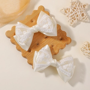 Dettaglio di fermagli per capelli con fiocchi di pizzo crema su vassoio di legno
