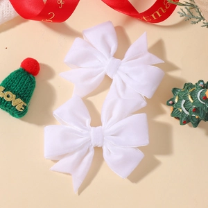 Gros plan d'une paire de nœuds à cheveux en velours blanc avec décor de Noël festif