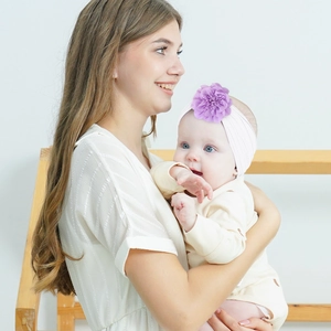 Infant floral headband set with purple flower detail worn by baby in a warm home setting
