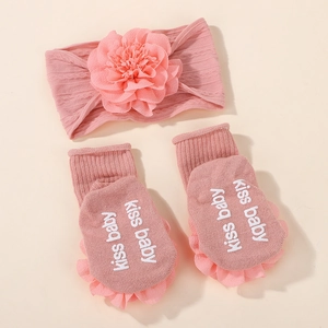 Close-up of pink knit baby headband with layered flower and socks featuring ruffled cuffs