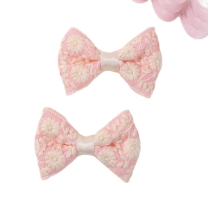 Paar roze geborduurde haarstrikken met delicate witte kanten bloemenpatronen