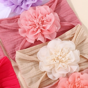 Detailed view of layered fabric flowers on elastic ribbed baby headbands in various colors