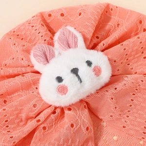 Close-up of pink knitted hollow-out baby hat with a cute 3D plush rabbit face