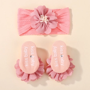 Detail of pink baby headband and socks set with floral accents and non-slip grippers