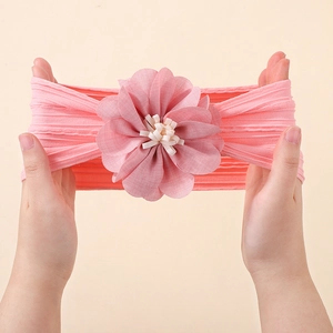 Detail showing the stretchability of the pink floral baby headband with elastic knit texture
