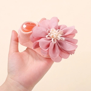 Detail of pink knitted baby sock featuring a large 3D fabric flower with yellow stamen