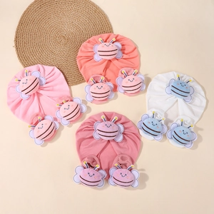 Detail of four sets of cotton baby beanies and matching socks with plush bees