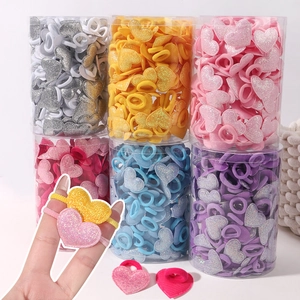 Détail d'élastiques à cheveux pailletés en forme de cœur avec emballage cylindrique coloré