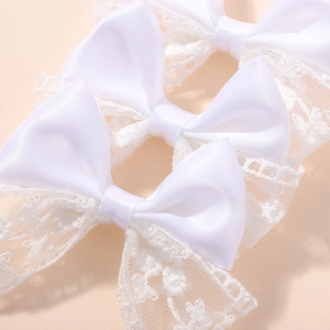 Detailed close-up of white satin and lace bow hair clip showing delicate fabric texture