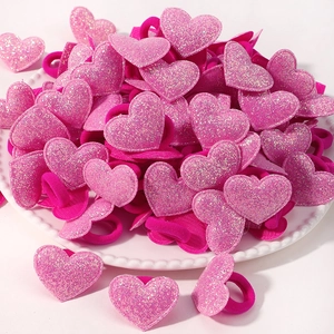 Gros plan d'élastiques à cheveux roses en forme de cœur à paillettes sur une assiette décorée