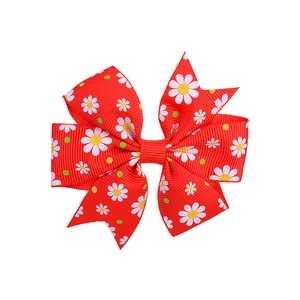 Close-up of red grosgrain bow hair clip with daisy floral print and ribbed texture