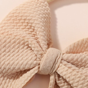 Macro shot of apricot bubble fabric texture and bow detail on nylon baby headband