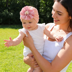 Close-up of pink knit baby turban hat with a layered floral accent and pearl bead