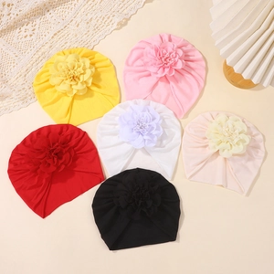 Vista plana de turbantes para bebés coloridos con flores de tela en seis tonos suaves
