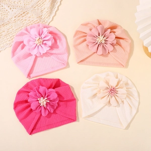 Detail of four baby turbans in pink and cream with large 3D floral accents and ribbed texture
