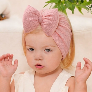 Pink infant turban hat with large bow made of textured jacquard knitted cotton fabric